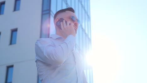Handsome Man of American Appearance Standing on a of Sunlight and Talking. handsome man of American appearance standing on a of sunlight and talking on the phone. Successful executive talking outside on a warm sunny day