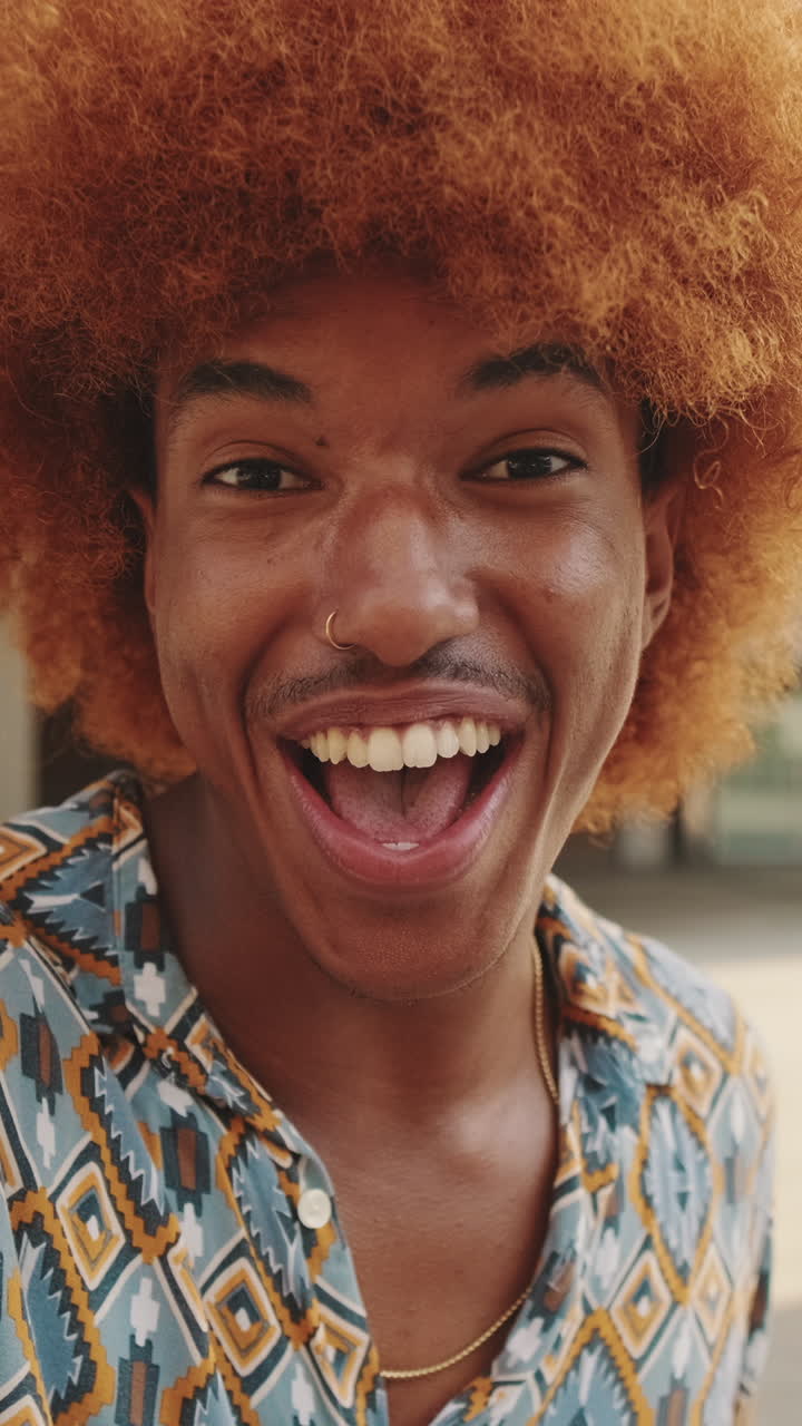 Giovane uomo felice con afro che sorride e ride alla telecamera