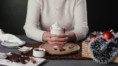 young woman's hands decorating a cup of hot chocolate