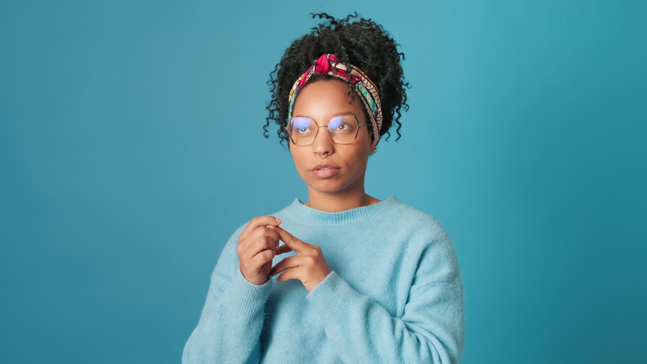 Thoughtful Young Woman with Glasses Pondering Against Blue Background