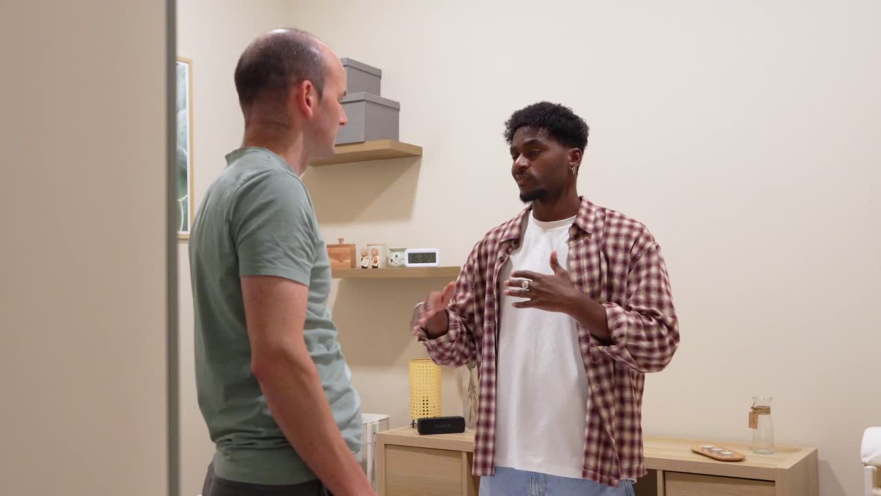Two Men Talking and Gesturing While One Offers Support