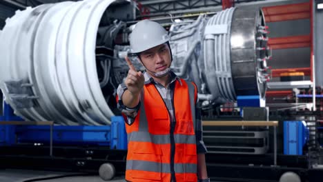 asian male engineer with safety helmet disapproving with no index finger sign while standing with airplane engine maintenance conducted, analytics checking the turbine
