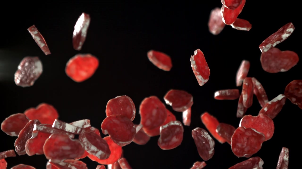 Slow Motion Salami Slices Falling Against a Black Background