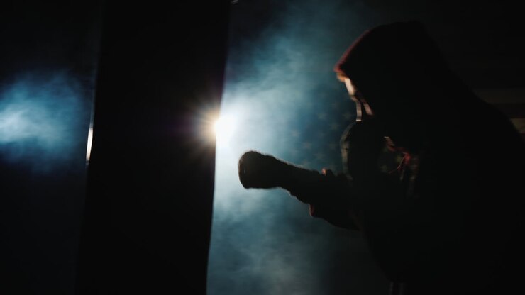 Silhouette di un combattente Trinity in palestra - colpisce un sacco da boxe.