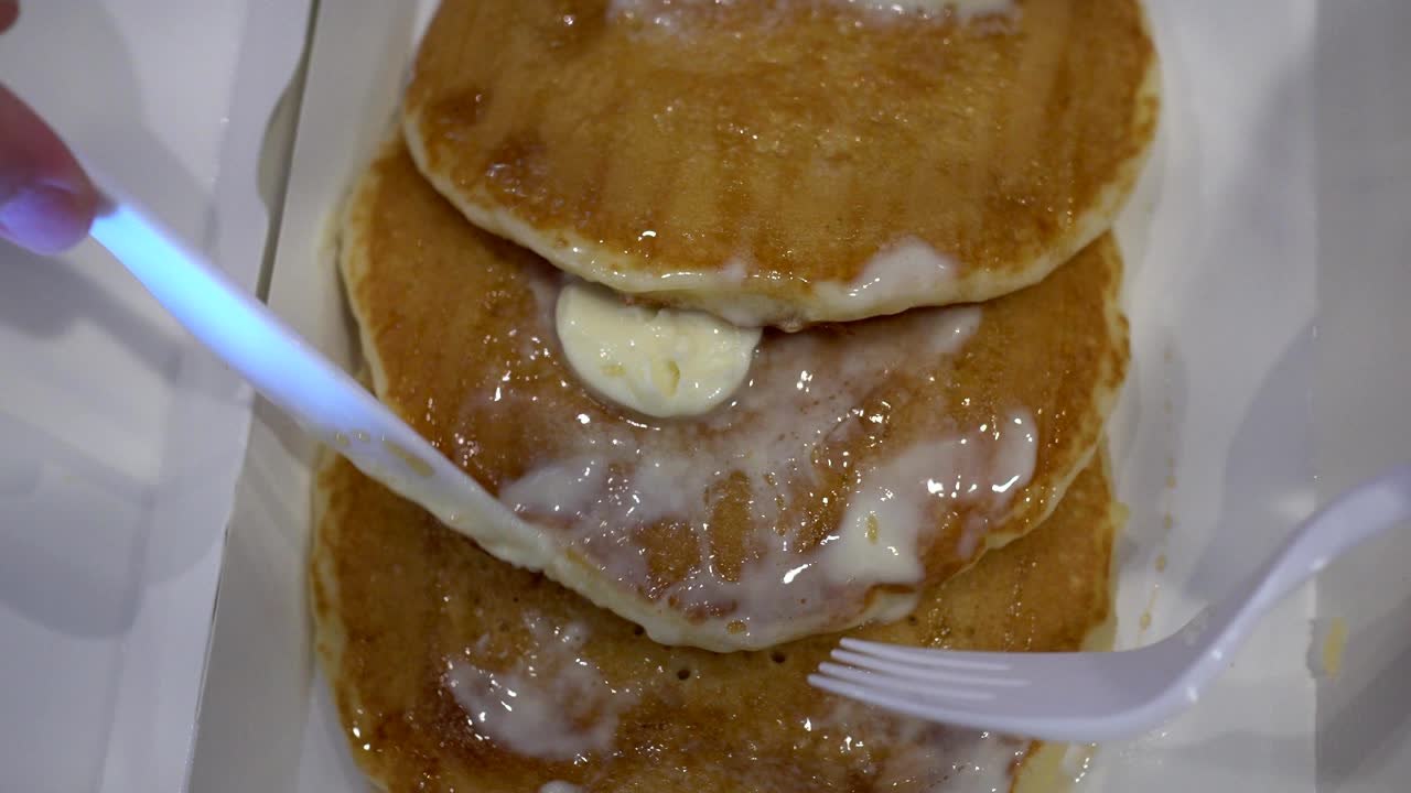 아이는 칼과 포크로 아이의 손을 고 크림을 팬케이크에 뿌립니다.