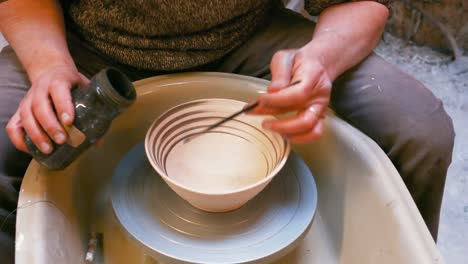 male artist painting on earthenware bowl