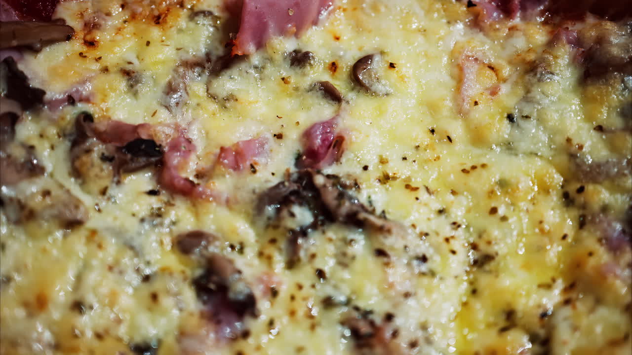 Close up of a pizza with ham and cheese on a table at a restaurant