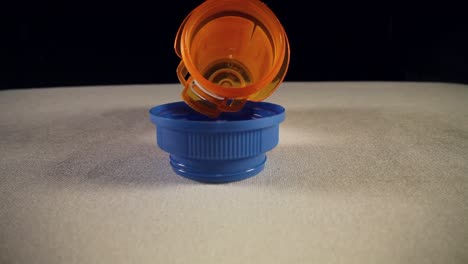 moving past empty blue bottle cap, slowly pushing into the entire length of a orange prescription pill bottle