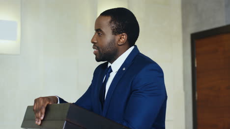 african american businessman speaker on a podium at a conference and interacting with people in the hall during his speech