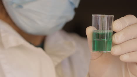 scientist analysing a green sample of water, closeup