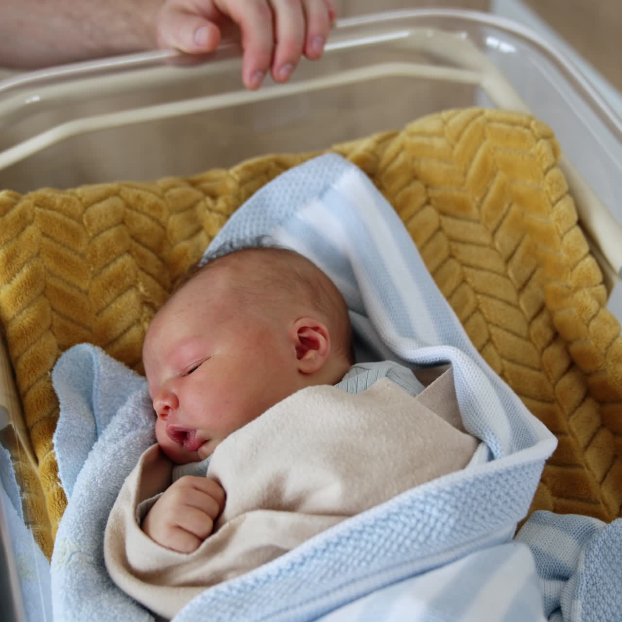 Un bel bambino caucasico dorme in una culla. Un uomo non riconosciuto siede vicino alla culla del suo neonato. Vista dall'alto