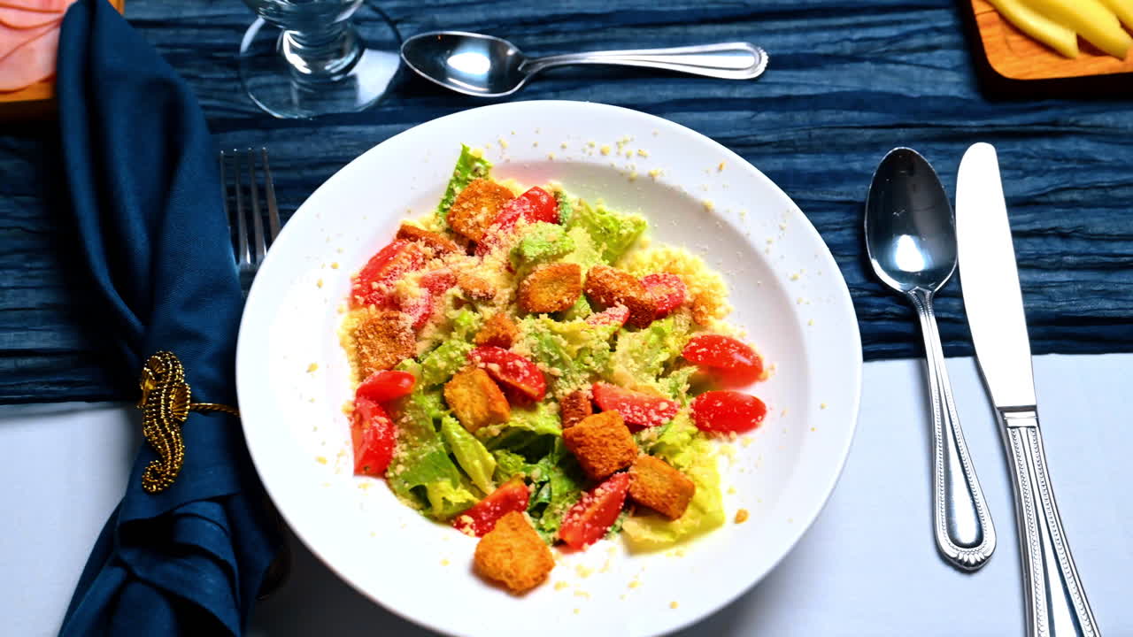 Verse Caesar salade met croutons en cherrytomaten. Bovenaanzicht van een witte kom met Romeinse sla, Parmezaanse kaas, geroosterd brood en gesneden tomaten op een gedekte tafel