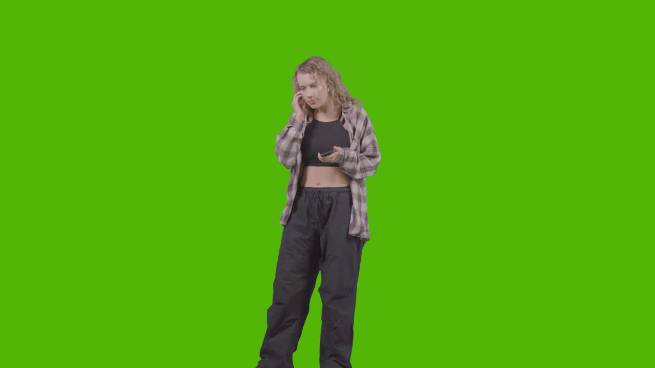 Full Length Studio Shot Of Young Woman Listening To Music On Mobile Phone And Dancing Against Green Screen 1