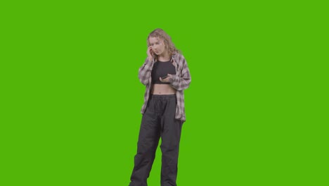 Studioaufnahme-In-Voller-Länge-Einer-Jungen-Frau,-Die-Musik-Auf-Dem-Handy-Hört-Und-Gegen-Green-Screen-1-Tanzt