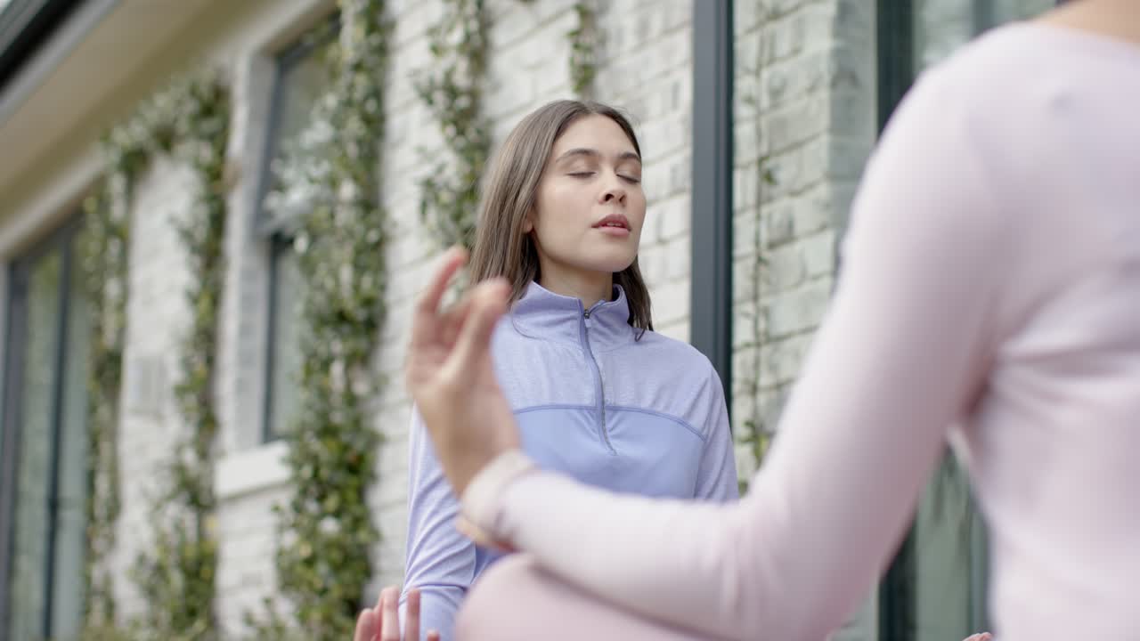 Eine Ausbilderin hebt die Smartwatch-Hand und leitet eine Schülerin an, die auf der Terrasse tief durchatmet, um zur Ruhe zu kommen