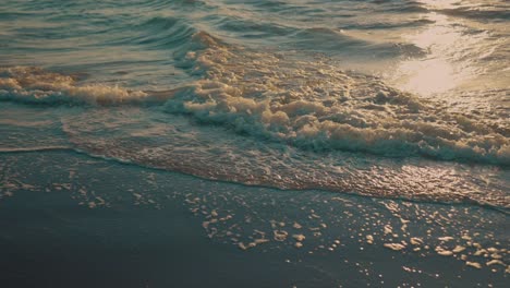 Olas-Lavando-En-La-Playa-Durante-La-Puesta-De-Sol,-Cámara-Lenta