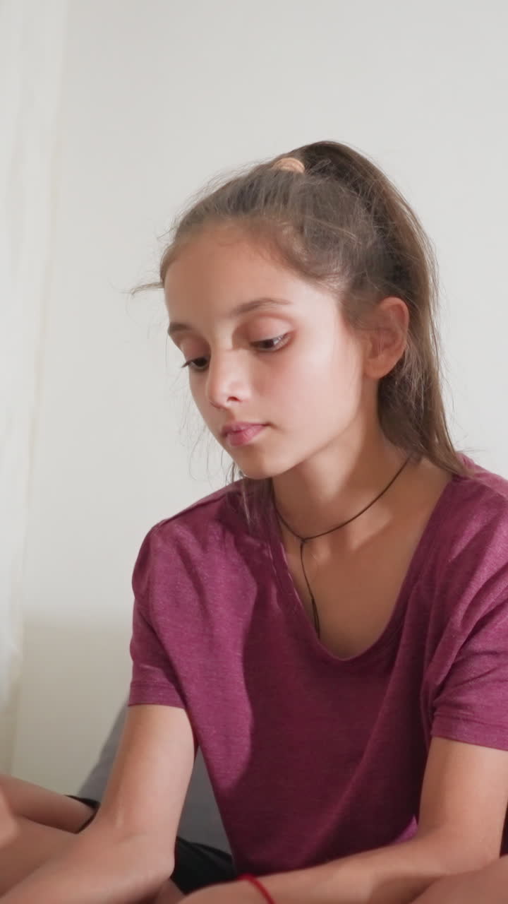 Un niño pequeño sentado en un sofá, concentrado en estudiar y leer un libro, mientras su primo, sentado a su lado con las piernas cruzadas, escribe atentamente con un bolígrafo en un espacio interior tranquilo y lleno de concentración.