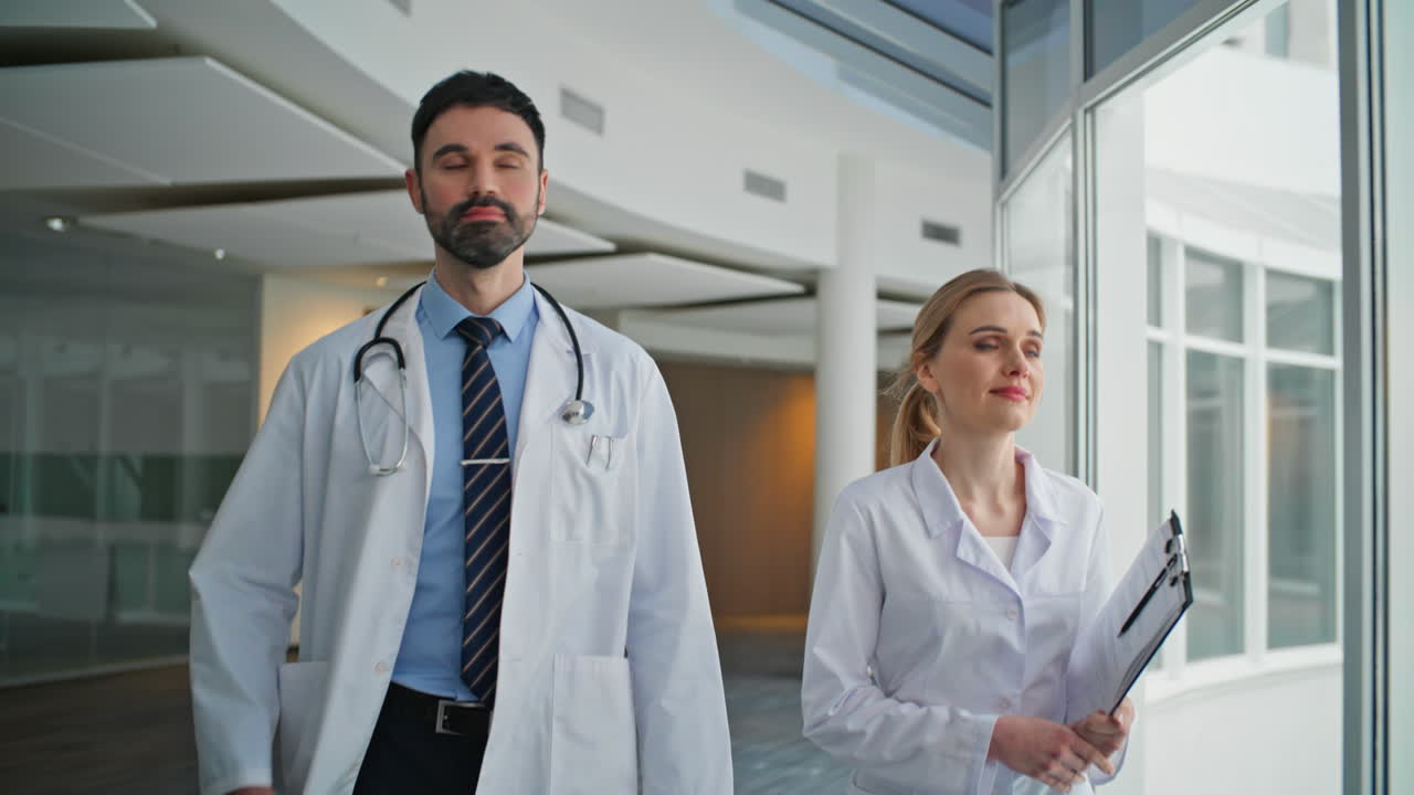 Personale della clinica che cammina insieme nel corridoio, primo piano. Due medici che lavorano nel settore sanitario
