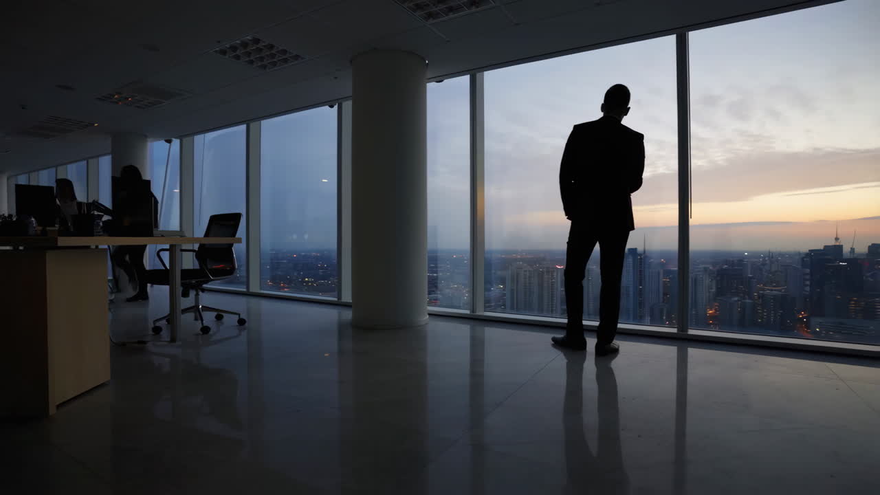 Businessman Silhouette Gazing at City Skyline from Office Window at Sunset
