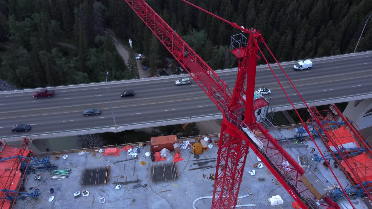 Crane with workers by busy highway bridge construction zone above