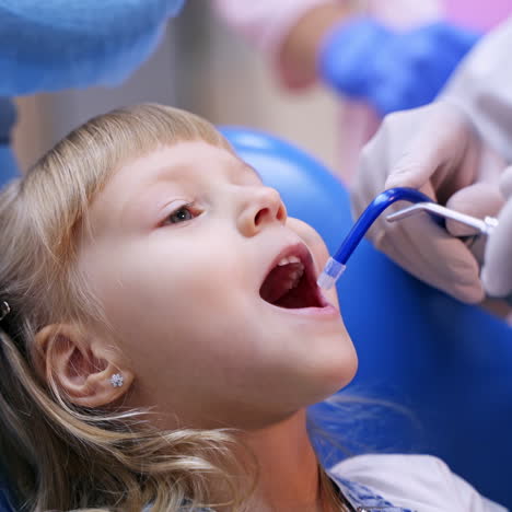 Little child in stomatology chair - close up. Cute blonde girl opened her mouth for teeth check up. Health concept video.