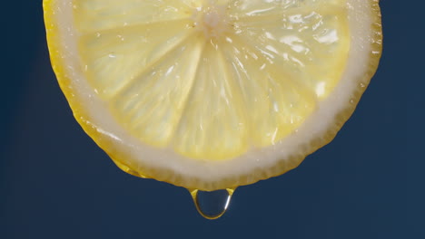 slow motion macro shot of flowing water from lemon slice on blue-black background