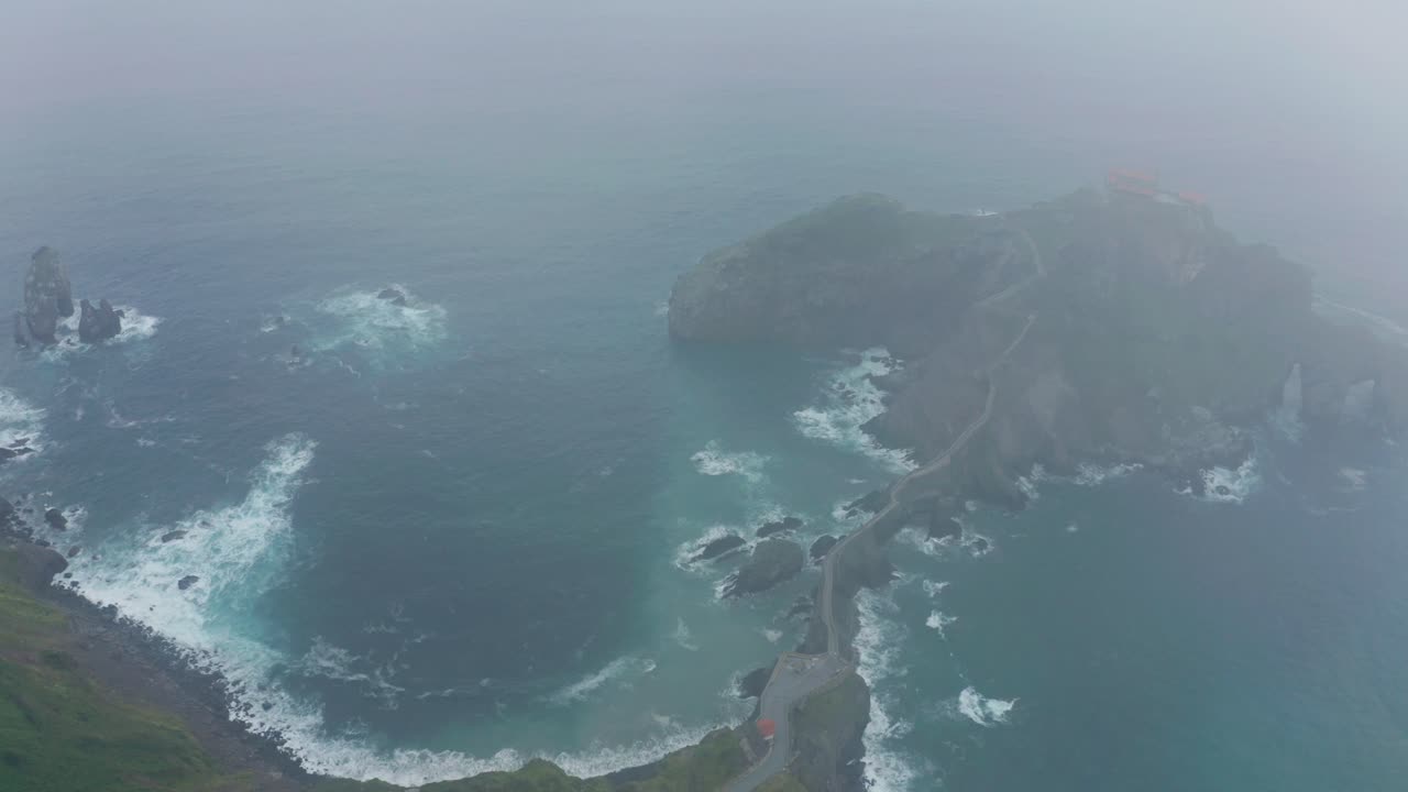 하늘 아래의 산책로와 함께 녹색 산 근처의 파동하는 바다