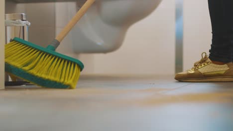Female-Worker-Cleaning-The-Bathroom-Floor-With-A-Bathroom-Sweeping-Broom---close-up