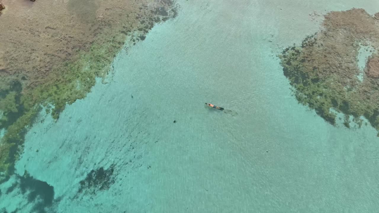 hombre buceando a través de arrecifes poco profundos con marea baja