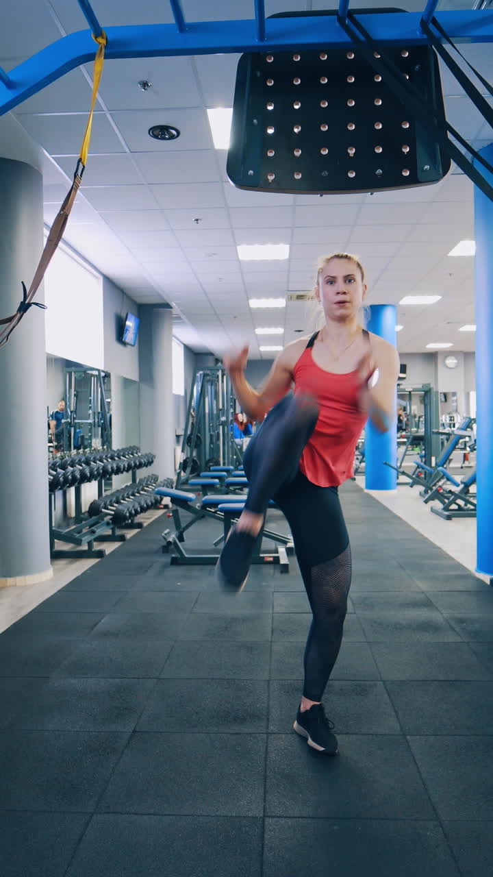 Full-length portrait of sportswoman in gym. Young girl doing exercise alone in a modern fitness club. Training workout indoors. Vertical video