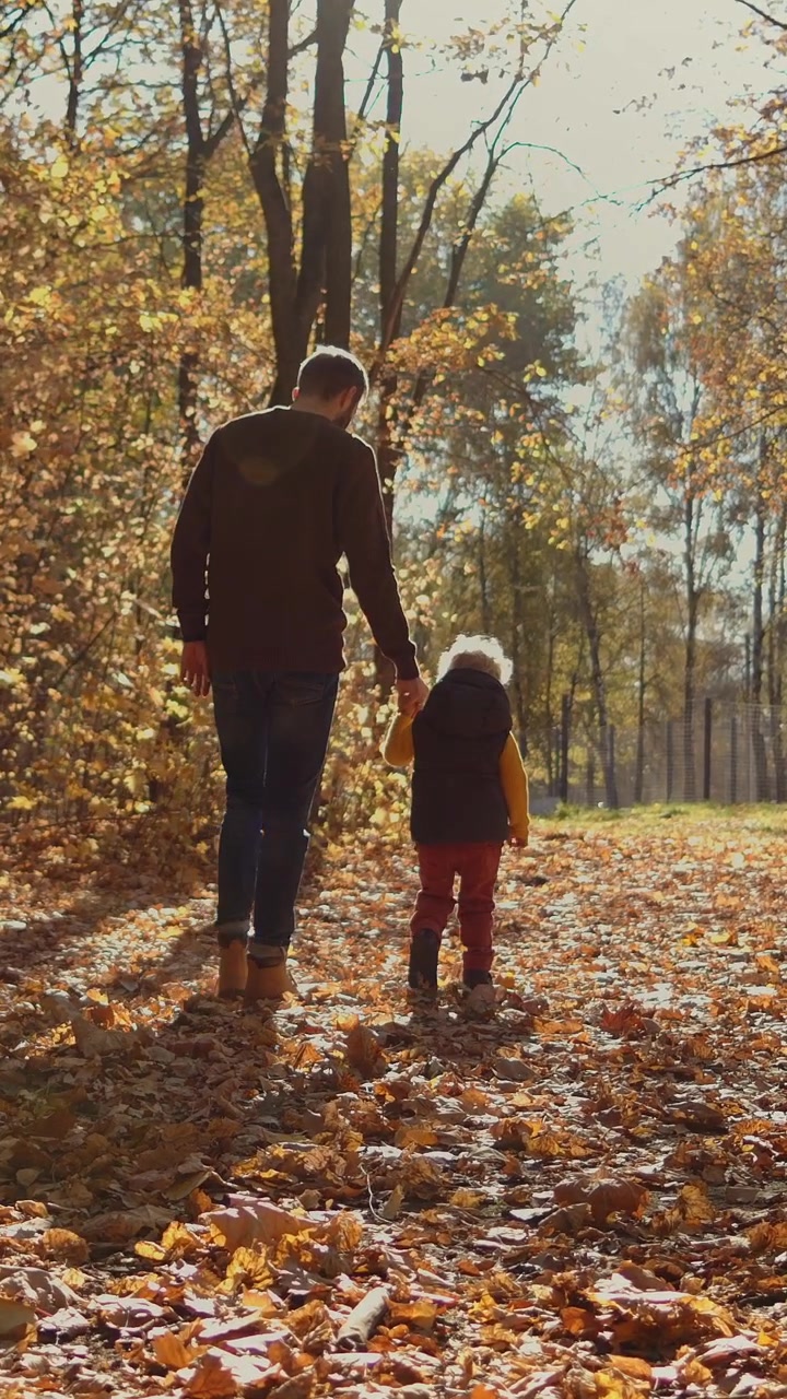 Padre e figlio che passeggiano insieme nel bosco autunnale