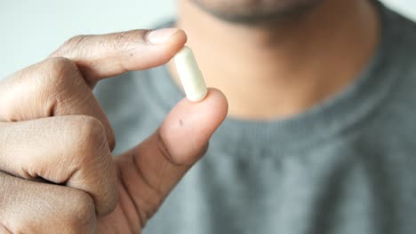 person holding a white capsule