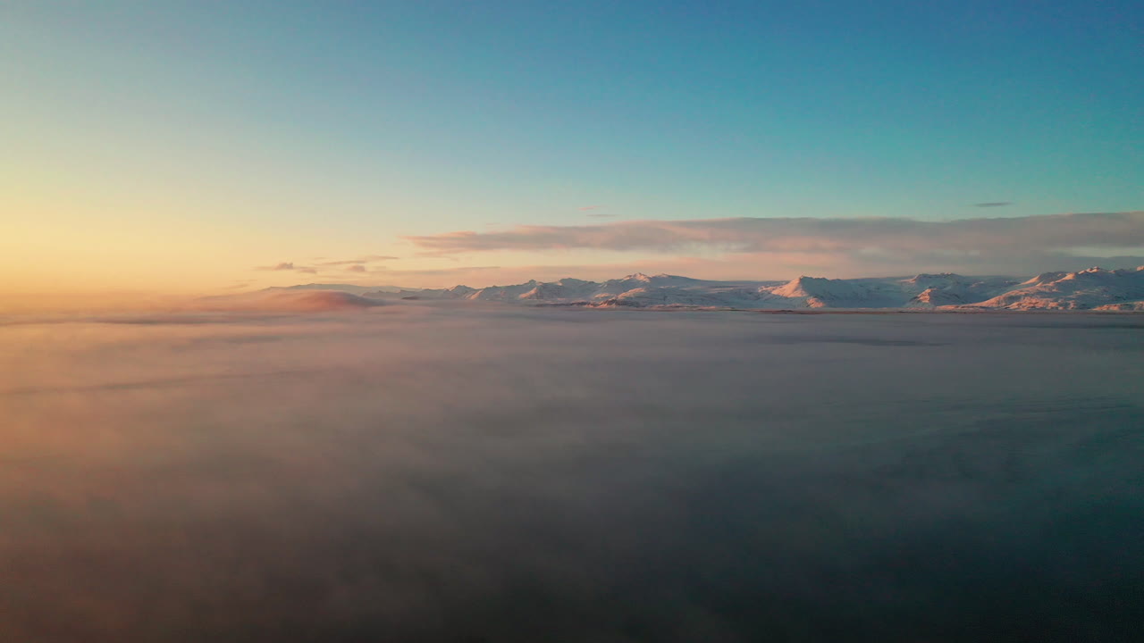Drone Flying over low clouds towards Vatnajokull Glacier Cap in South Iceland - aerial shot