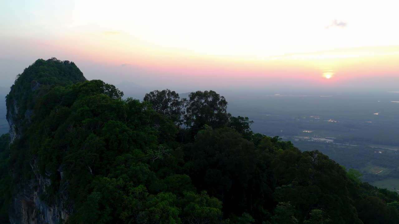 drone view of a sunset over a Thai mountain and a large plain full of greenery