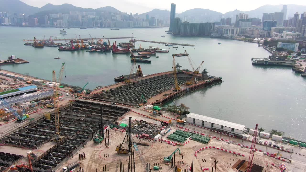 Converting an old runway strip into a Housing and business district at Kai Tak downtown Hong Kong, with vast infrastructure development land and an underwater tunnel laying operation, Aerial view.