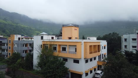 panoramic view of residential buildings with mountains in the background shrouded by fog and clouds in trimbakeshwar