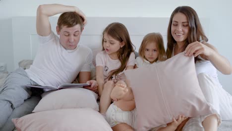 happy family spending time in bedroom with children and reading book