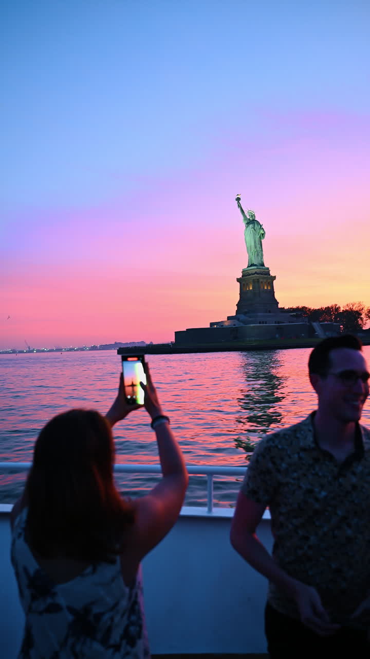New York, USA, 9 agosto 2025: Turisti su una barca che scattano foto al tramonto della Statua della Libertà. Persone sul ponte di un traghetto osservano e immortalano la Statua della Libertà durante un tramonto dai colori vivaci.