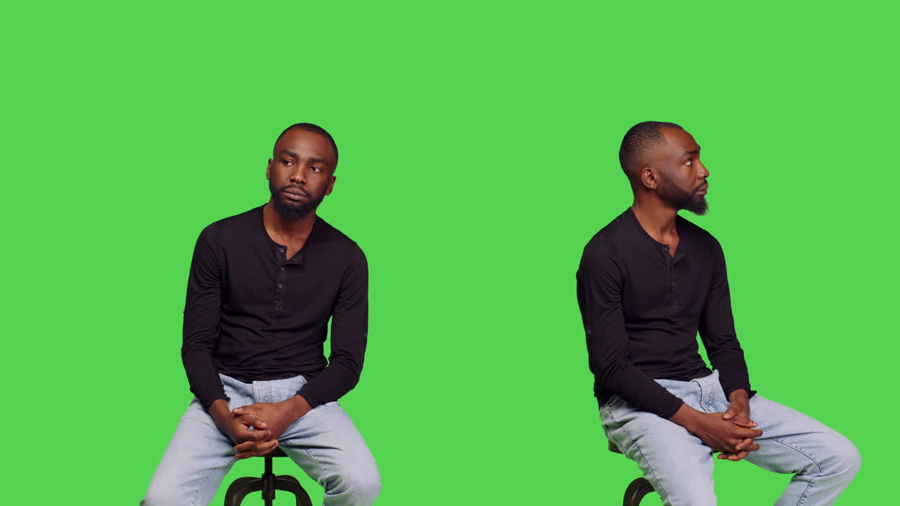 Man sitting on a stool in front of a green screen
