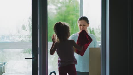madre y hija pequeña lavan la ventana