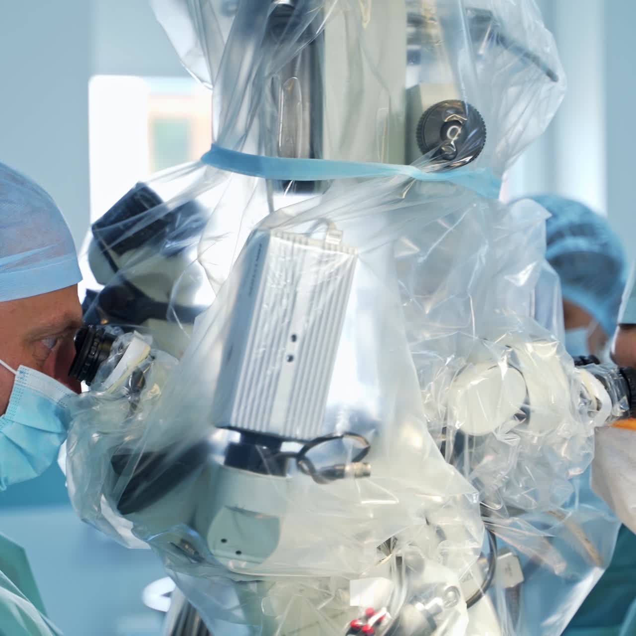 Doctors sit at opposite sides of a modern technological microscope during operation. Focused doctors look attentively into binoculars. Close up