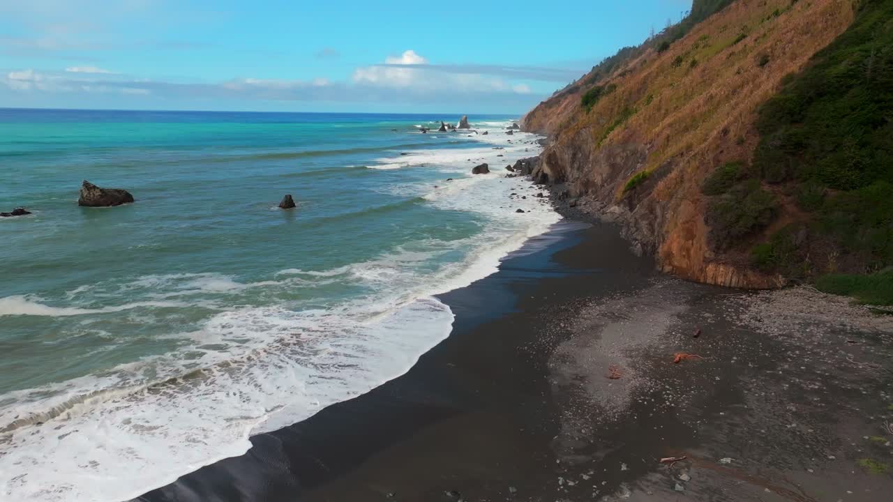 Waves crashing surf black sand rugged coastline sunny morning blue sky mist fog layer California aerial drone USAL Beach Campground Lost Coast Trail PNW boulders rocks mountainside forward motion