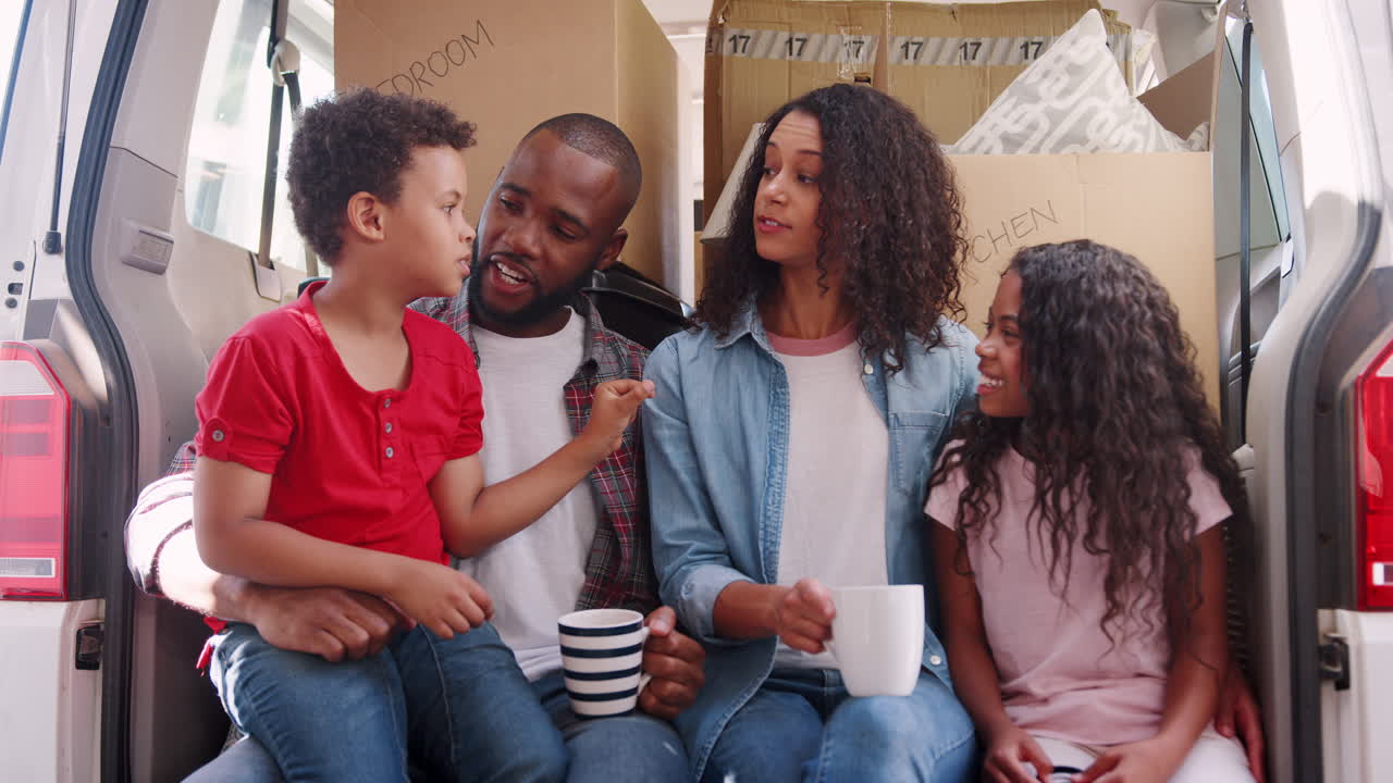 fotografía en cámara lenta de una familia sentada en la parte trasera de un camión de mudanzas el día de la mudanza