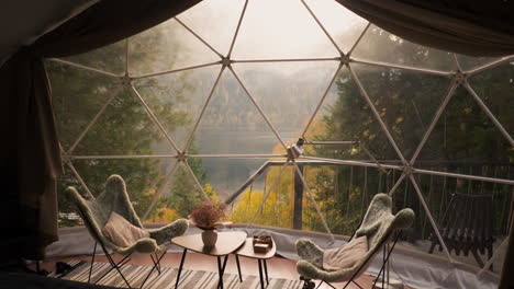 lunch space on glamping house terrace for tourists. low table with soft chairs around to enjoy enchanting view of lake. glamping hotel room for rent