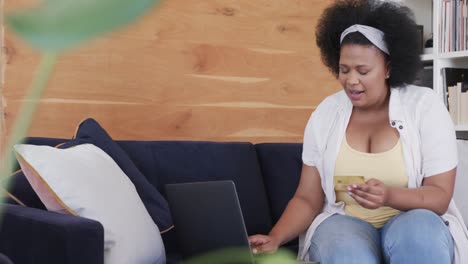 mujer afroamericana de talla grande que usa una computadora portátil para comprar en línea, inalterada, en cámara lenta