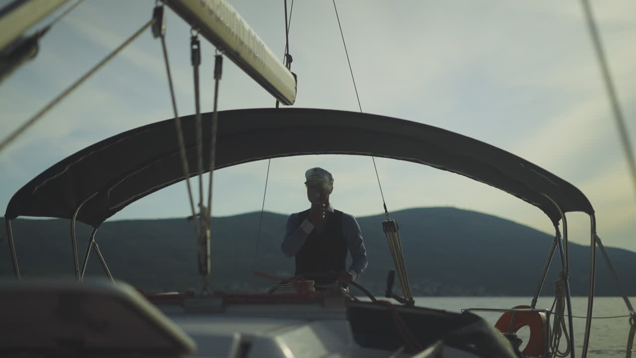 Man Steering a Yacht at Sunset