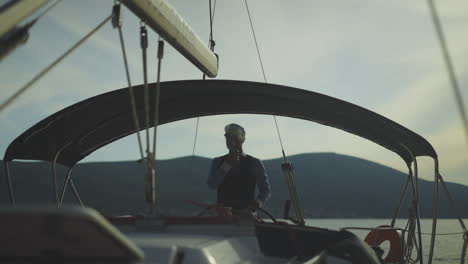 man steering a yacht at sunset