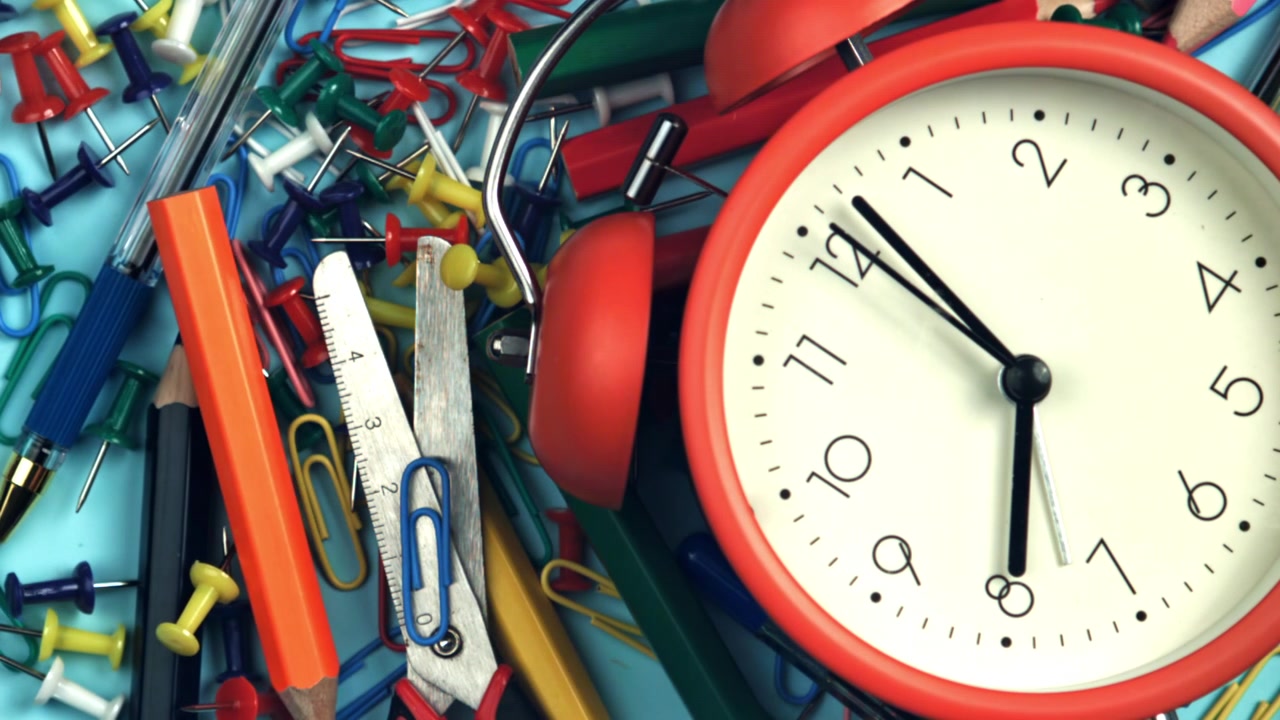 Alarm Clock Ticking Among Colorful Office Supplies