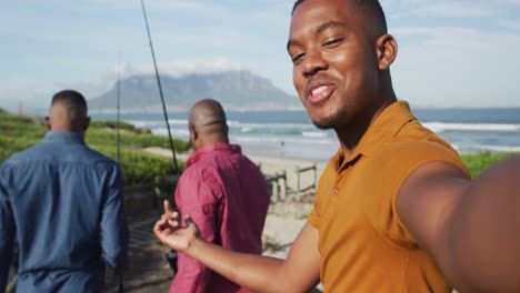 African-american-senior-father-and-two-teenage-sons-standing-on-a-beach-fishing-and-talking