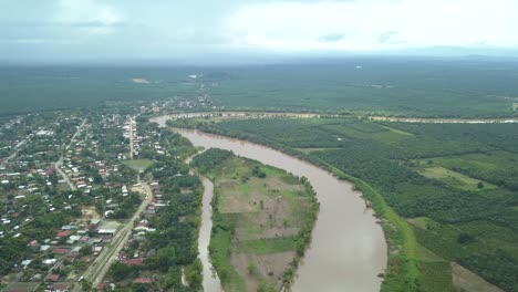 big river next to a small town and a green forest